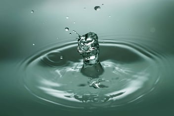 Close-up shot of a drop splashing in water.